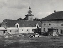 věž kostela vykukující za domem