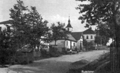 věž kostela vykukující za domy