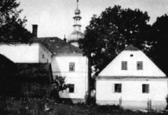 věž kostela vykukující za domy