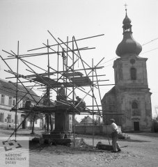 oprava poraženého morového sloupu s kostelem v pozadí