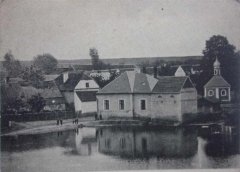 historické foto synagogy, adaptované už na obytný domek (uprostřed snímku, se dvěma okny a valbovou střechou)