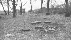 pobořená ohradní zeď a poražené náhrobky