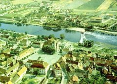 letecký pohled na město s dosud stojící zástavbou; čarou je vyznačeno, kudy povede plánovaný most, kaple je označena šipkou