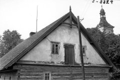 jeden z domů ve vsi s kostelní věží v pozadí